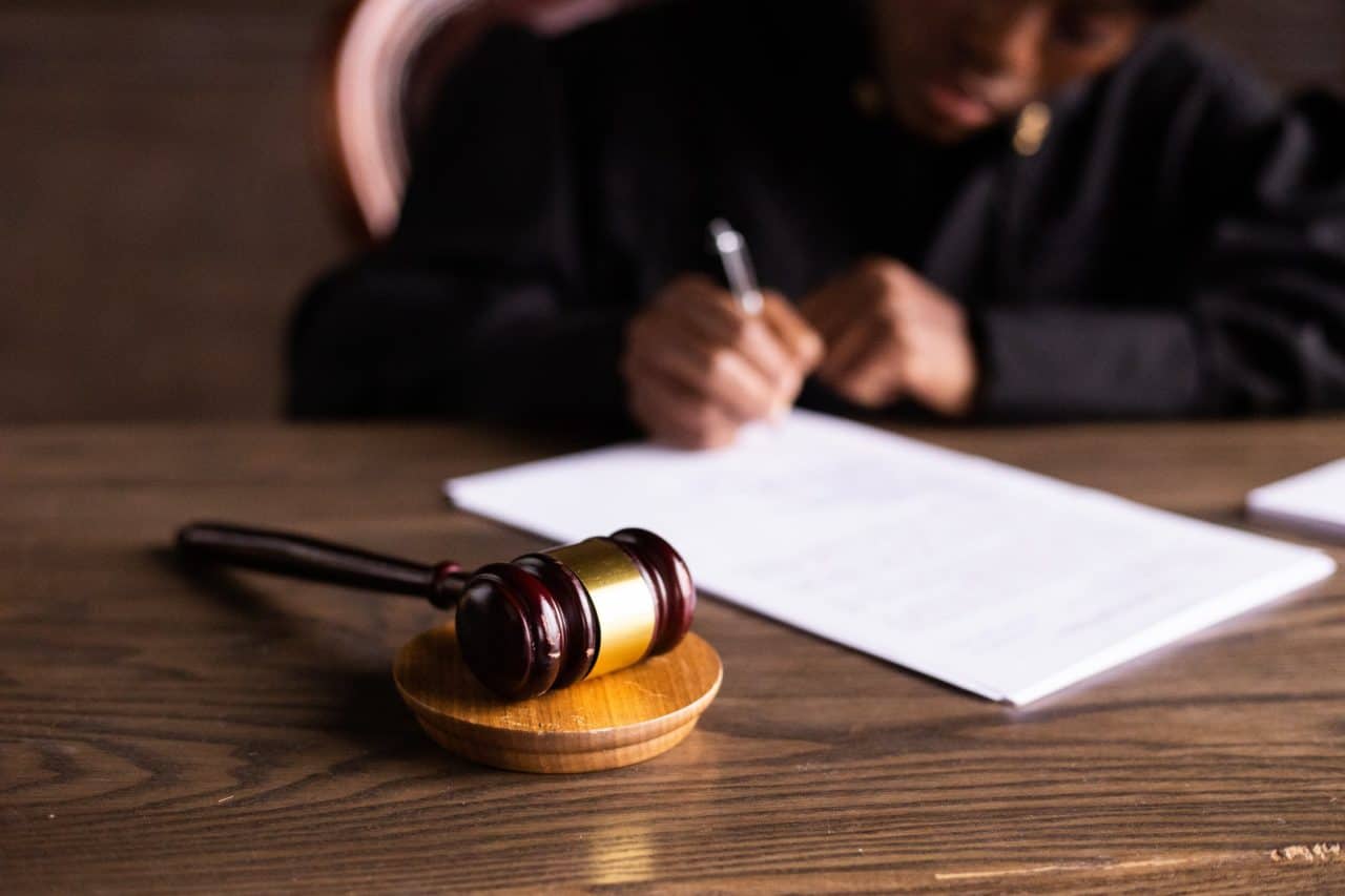 stock image showing a gavel on a desk and a judge writing a felony indictment